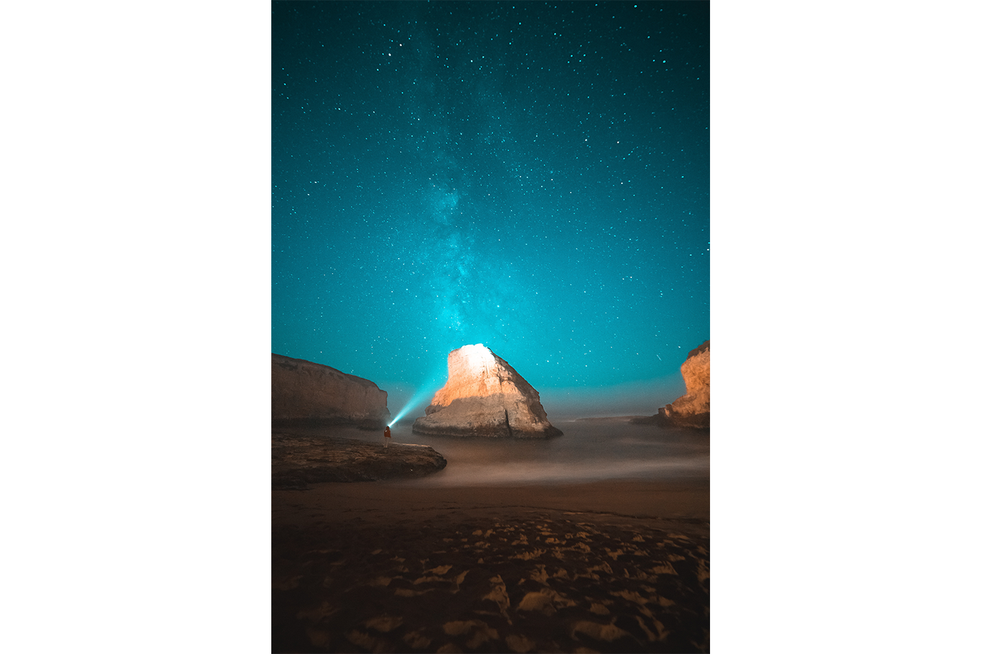 a man on a beach at night, illuminating a sea stack under the milky way, art, kanvas tablo